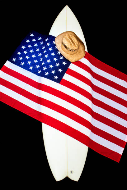 USA Flag on a white surfboard with a straw hat, black background, and a guitar.