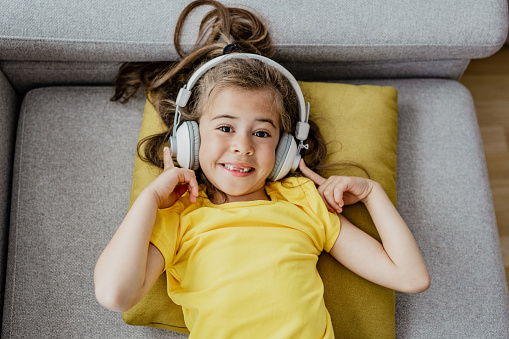 Close up portrait of cute girl listening music using headphones