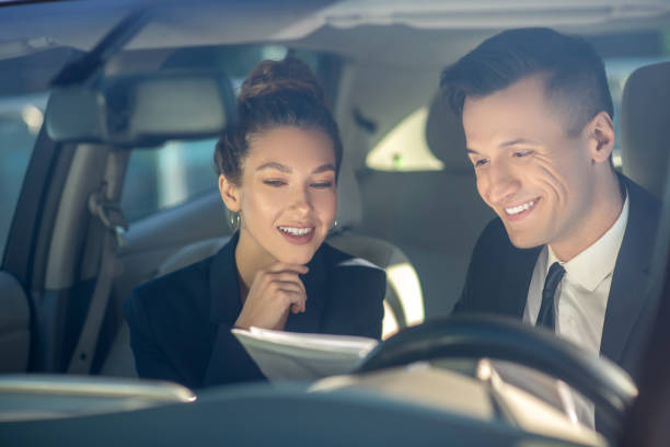 istock Young successful woman and man reviewing documents in car 1244848358