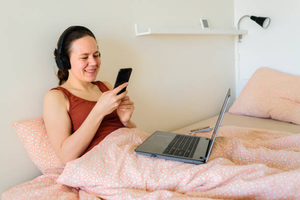 istock Woman working from home in her bed. Using phone for internet 1244854261
