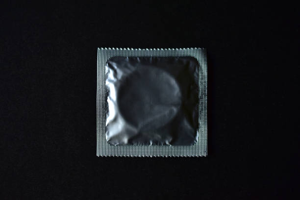 nouveau préservatif brillant sur un fond noir - condom photos et images de collection