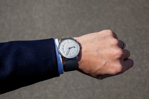 A simple three-hand watch worn on the hand of a suit