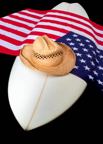 istock USA Flag on a white surfboard with a straw hat, black background, and a guitar. 1244870072