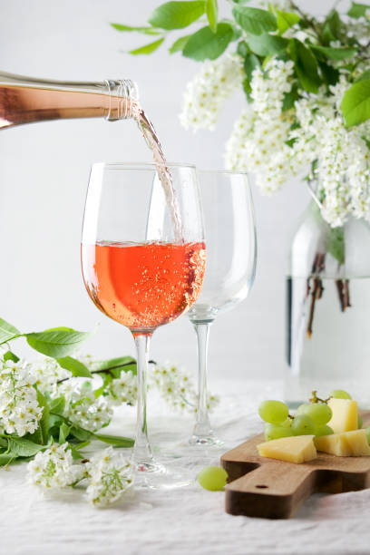 istock Rose wine pouring into glass on white table surrounded by blossoming branches 1244879623