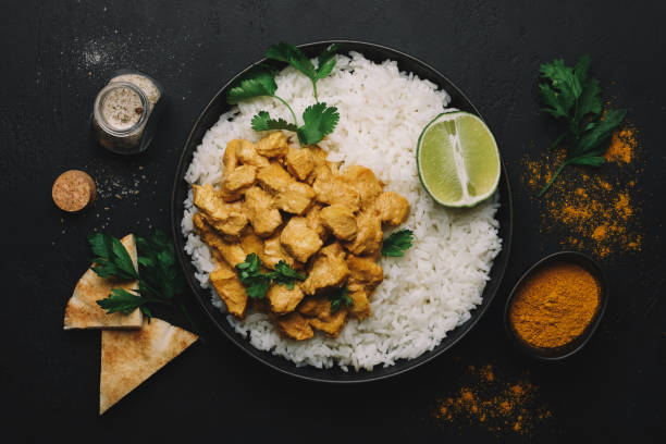 Indian Butter chicken curry with basmati rice in bowl on black background. Flat lay, copy space