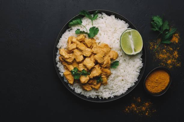 istock Indian Butter chicken curry with basmati rice in bowl on black background. Flat lay, copy space 1244885025