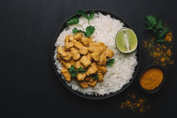 Indian Butter chicken curry with basmati rice in bowl on black background. Flat lay, copy space stock photo