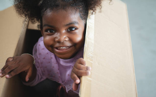 istock Dark skinned child girl playing in cardboard box 1244886681