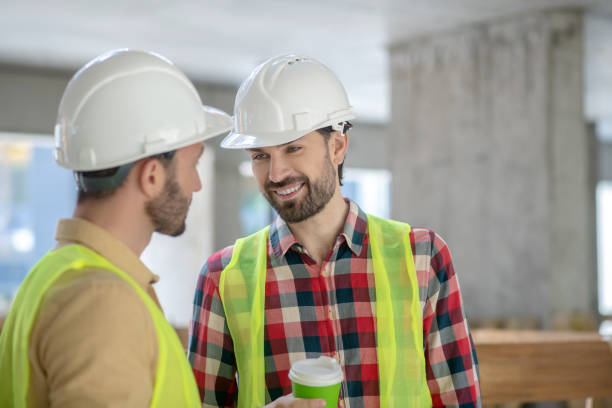 istock Building workers in yellow vests and helmets drinking coffee, talking, smiling 1244892267