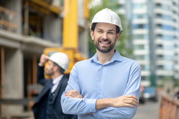 istock Foreman standing with folded arms, building supervisor standing behind him, looking at the building 1244893337