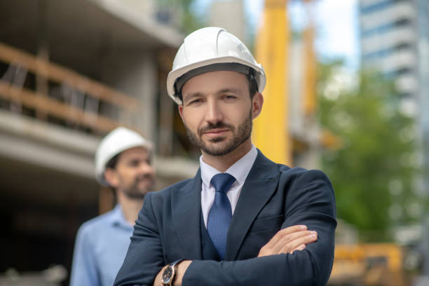 istock Building supervisor standing with folded arms, foreman looking sideways behind him 1244893339