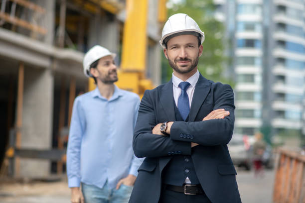 istock Building supervisor standing with folded arms, foreman looking sideways behind him 1244893343