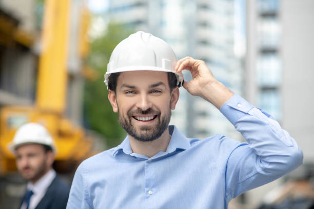 istock Foreman holding his helmet with one hand, smiling, building supervisor standing behind him 1244893349