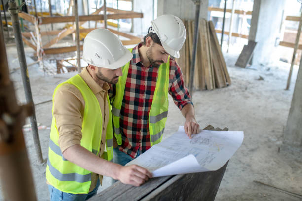 istock Building workers in yellow vests studying carefully blueprint, checking details 1244893898