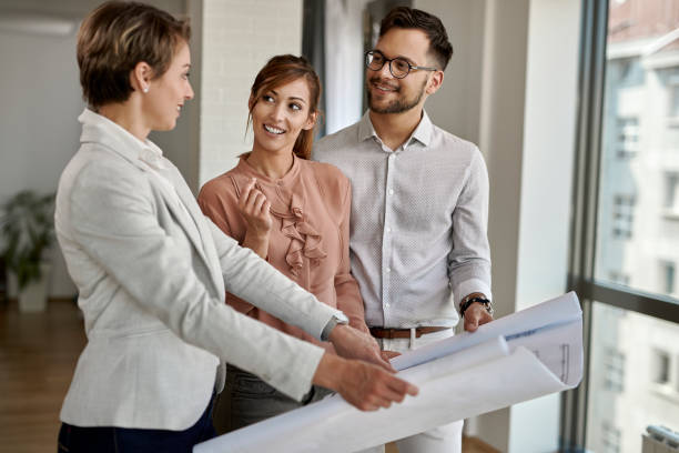 istock Happy couple talking to real estate agent while going through housing plans. 1244901519