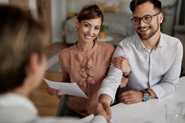 istock Young happy couple shaking hands with their insurance agent. 1244909748