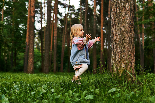 happy little girl runs after a butterfly in a nature park
