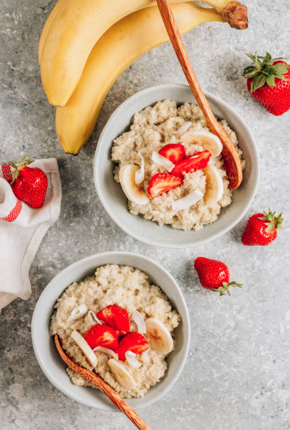 porridge di quinoa con latte di cocco e fragole fresche su sfondo grigio chiaro. colazione sana senza lattosio e glutine. - oatmeal heat bowl breakfast foto e immagini stock