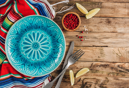 Entorno de mesa mexicano festivo. Plato y cubiertos con servilleta de colores sobre fondo rústico de madera. Plano. photo