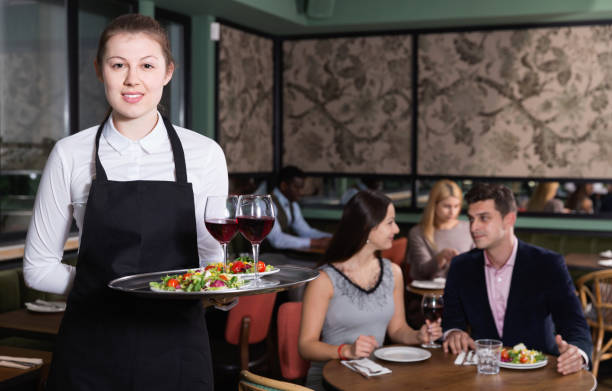 istock Attractive young waitress with serving tray welcoming in restaurant 1244932820