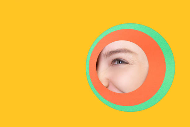 istock Female eye peeking throught circle in yellow background 1244934194