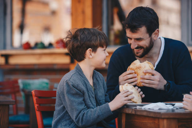 Father and son eating food inside a restaurant stock photo