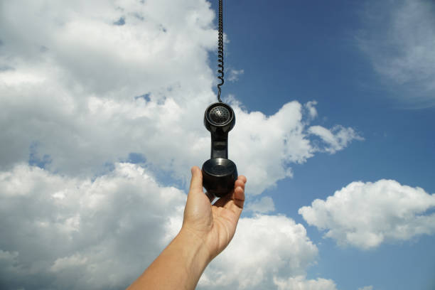 vintage black phone with line hanging from the sky. Conceptual photography talking to someone from above