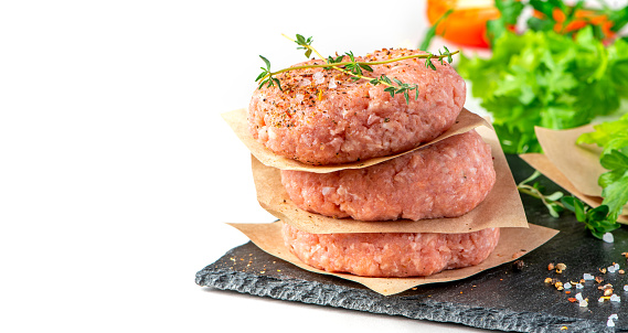 A stack of raw pork cutlets close-up, free space for text. Raw meatballs for grill or burgers on a white background, copy space. Minced pork meat.
