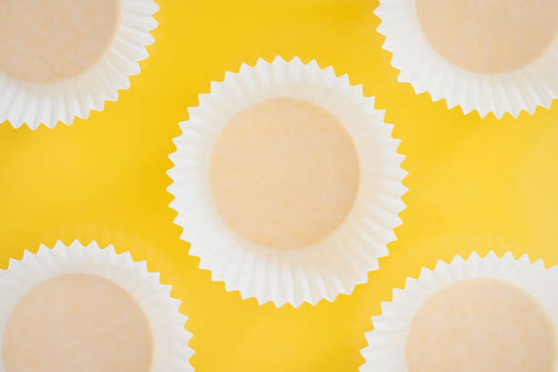 istock white cupcakes paper packaging background. cupcake foil on yellow background. cupcake cups, rolling pin, whisker. Happy food concept. Baking concept. 1244963808