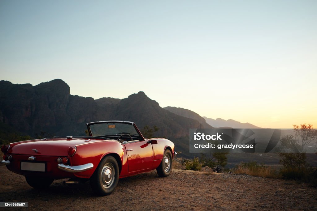 Road tripping old school style Shot of a vintage car parked on the side of a mountain Car Stock Photo