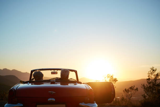 Starting a new chapter titled “Adventure” Shot of a senior couple enjoying the sunset during a roadtrip convertible photos stock pictures, royalty-free photos & images