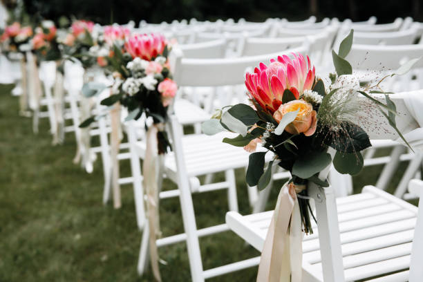 istock Decorated luxury wedding ceremony place in the garden. White empty chairs decorated with flowers. 1244997252