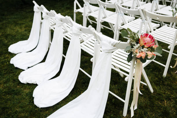 istock Decorated luxury wedding ceremony place in the garden. White empty chairs decorated with flowers. 1244998363