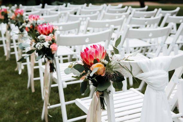 istock Decorated luxury wedding ceremony place in the garden. White empty chairs decorated with flowers. 1244999470