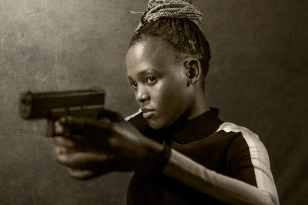 特別な連邦捜査官や拳銃を指す暴徒として銃を持っている若い魅力的で自信に満ちた黒人アフリカ系アメリカ人女性のハリウッド映画スタイルの肖像画 - gun women handgun armed forces ストックフォトと画像
