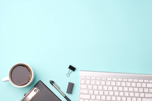 istock Flat lay top view office desk Workspace with blank clip board,computer keyboard, office supplies, pen,and coffee cup on light blue background 1245007073