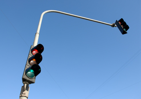 Two stoplights against a clear blue sky.