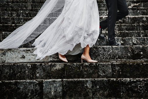 Bride and groom walking down the stairs. Wedding detail of shoes and legs.