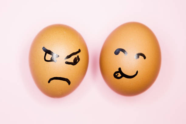istock Two eggs with mismatched cartoon faces, one smiling, the other scowling 1245038405