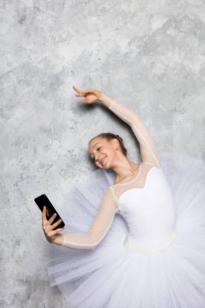 istock Young ballerina classical ballet dancer taking selfie mobile phone against rustic wall 1245043451