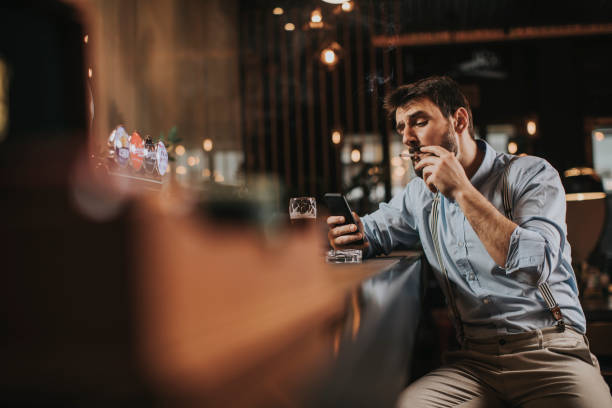 istock Man drinking beer, smoking cigarette and using mobile phone at pub 1245043916
