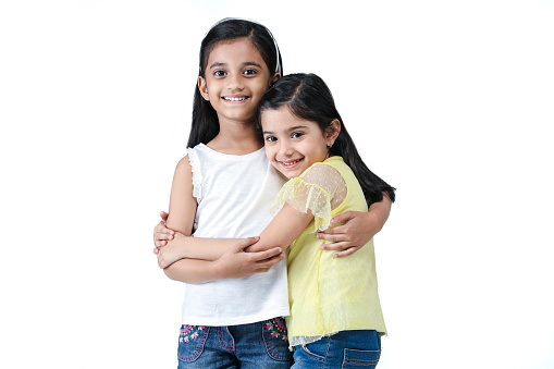 Indian Asian Studio portrait of two kid girls who are best friends hugging each other