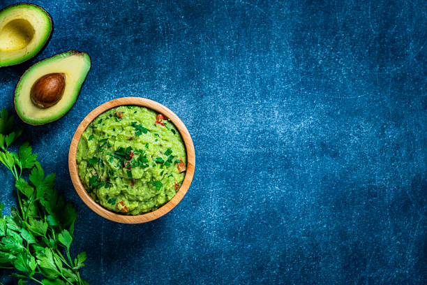 guacamole en un tazón de tiro desde arriba en la mesa de tinte azulado. copiar espacio - guacamole mexican cuisine avocado food fotografías e imágenes de stock