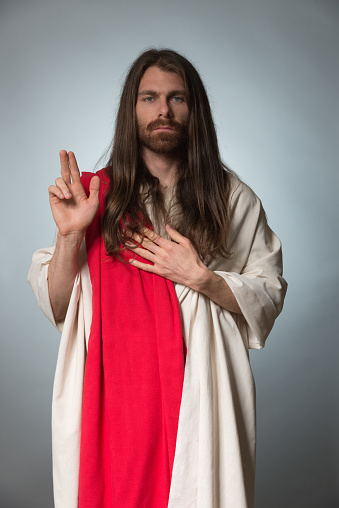 One person of aged 20-29 years old with with beard caucasian male worshipper standing in front of gray background who is contemplating who is praying