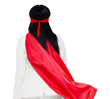 Rear view of aged 20-29 years old who is beautiful with black hair latin american and hispanic ethnicity young women heroines standing in front of white background wearing cape - garment who is conquering adversity with hand by side