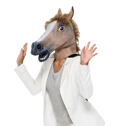 Waist up of aged 20-29 years old who is beautiful with long hair latin american and hispanic ethnicity female businesswoman in front of white background wearing horse costume who is bizarre and wearing horse mask