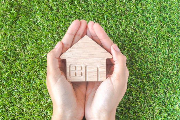 istock Home shaped on Woman's hand over green grass. Green Home Concept. 1245107483