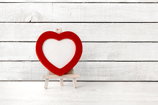 Red Heart Frame with wood art stand on white wood Background