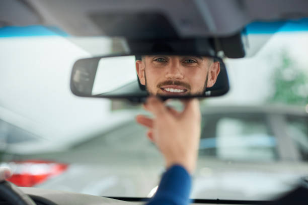 junger mann schaut in rückspiegel. - rear view mirror car mirror rear view stock-fotos und bilder