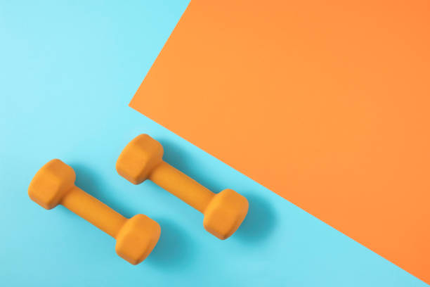 istock Dumbbells on Orange and Blue Background 1245117681